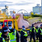 Police officers guarding an inflatable Loch Ness Monster at Govan Dry Dock after it was seized in a dawn raid