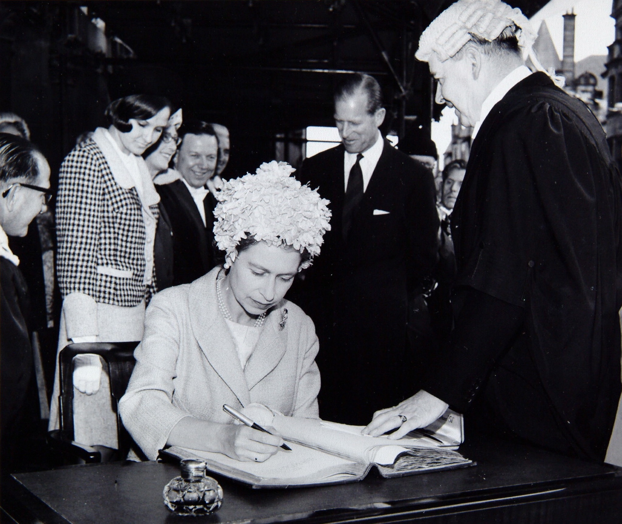 The Queen signing the visitors book as Prince Philip looks on, at the opening of Glasgow Airport.
