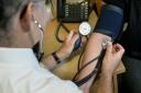 A doctor checking a patient's blood pressure. Credit: PA