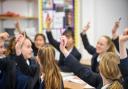 Pupils raising hands in class. Credit: PA