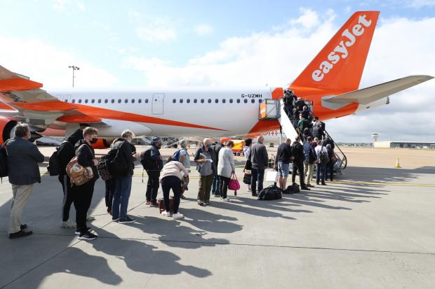 Glasgow Times: People queue to board an EasyJet plane. (PA)