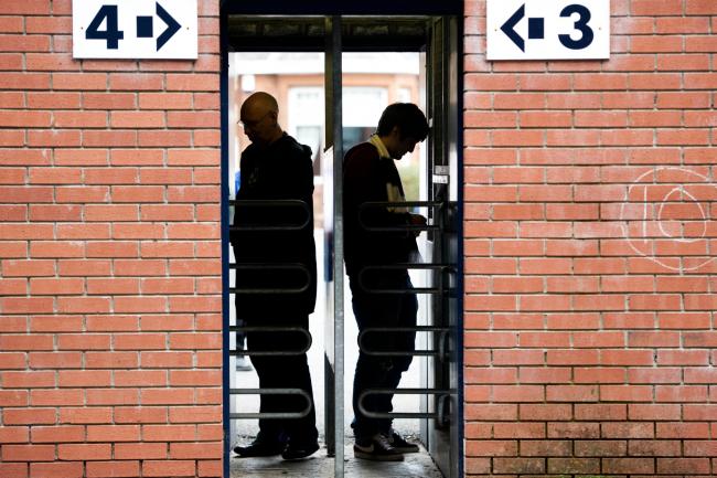 Two Kilmarnock fans squeeze through the turnstiles at Rugby Park