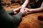 A couple holding hands in a restaurant. Credit: Canva