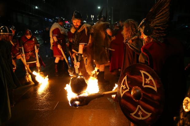 Glasgow Times: Shetland Vikings lighting their torches on Albion Street. [Photograph by Colin Mearns]