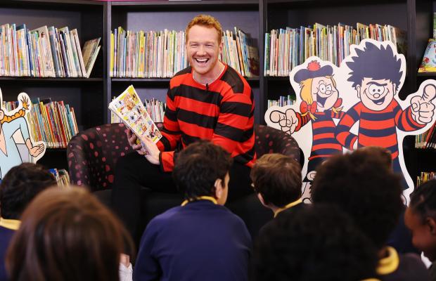 Glasgow Times: Olympic Gold Medallist, Greg Rutherford reads from the ‘World’s loudest ever comic strip’, which is part of a World Book Day edition of the Beano, to pupils of Laycock Primary school as part of the comic’s ‘Libraries Aloud’ reading initiative.