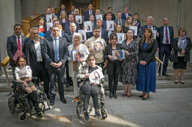 Glasgow Times: Caroline Lyon, from East Kilbride, (front, third from right) holds a photograph of her late daughter Louise Aitchison at the Scottish Parliament in Holyrood, Edinburgh, alongside other family members and MSPs.