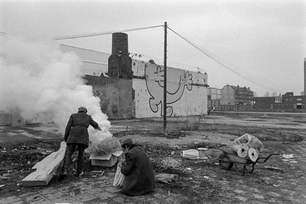 Glasgow Times: Burning scrap wire to retrieve the copper within, with ‘Glasgow’S miles Better’ logo on wall behind, in the Gorbals, Glasgow, Scotland, November 1993. Pic: Jeremy Sutton Hibbert