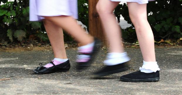 Glasgow Times: Two schoolgirls walking in uniform. Credit: PA