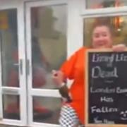 Jaki Pickett holds a sign reading 'Lizard Liz is dead' outside her Highland chippy