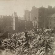 Two salvagemen on top of rubble in the aftermath of a fire on Robertson Street, 1900