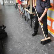 A janitor sweeping up in a school corridor  Photo: Martin Shields